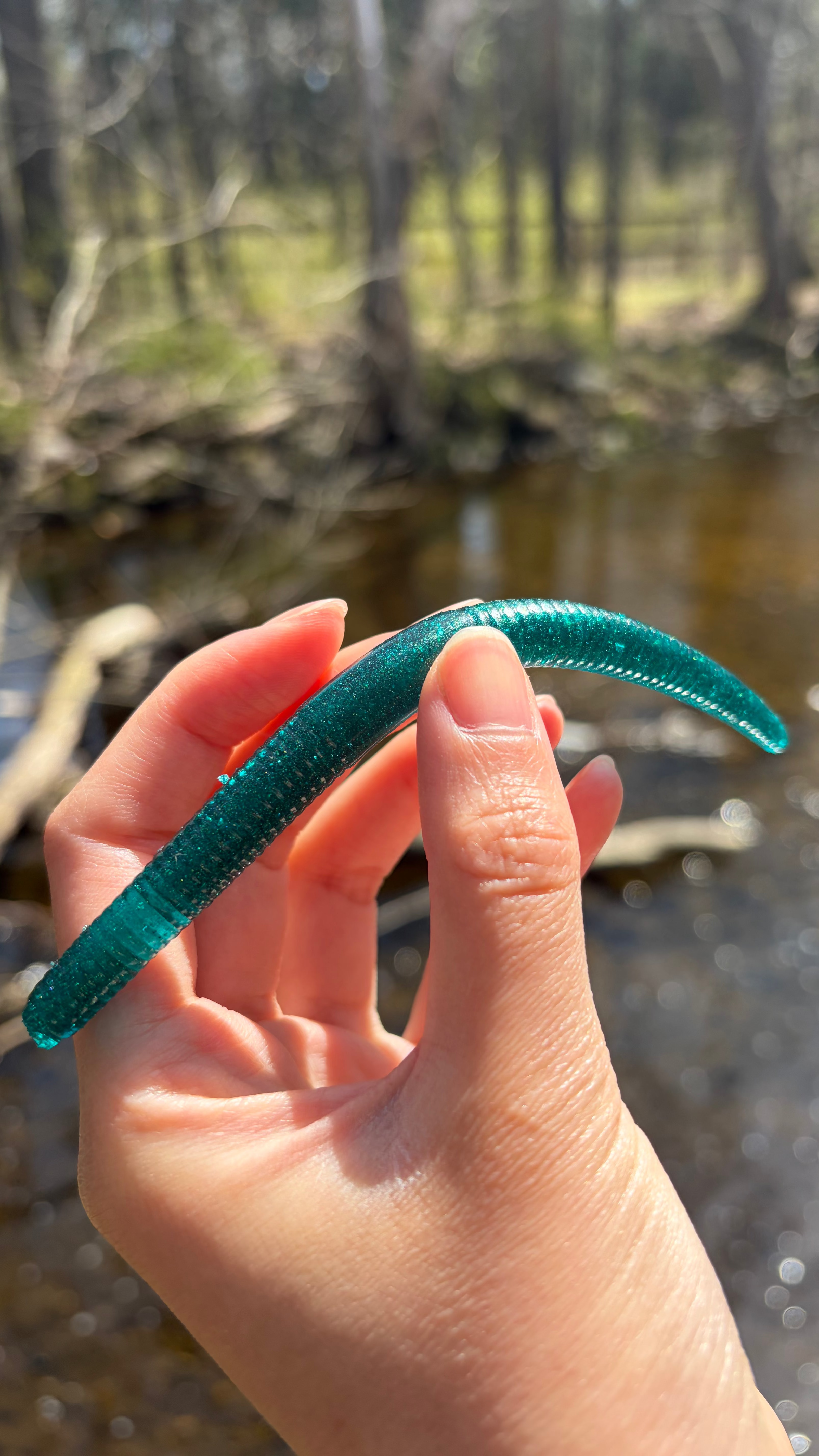 Midnight Blue Worm laying curved in person's hand to show the softness of SugarBait lures.